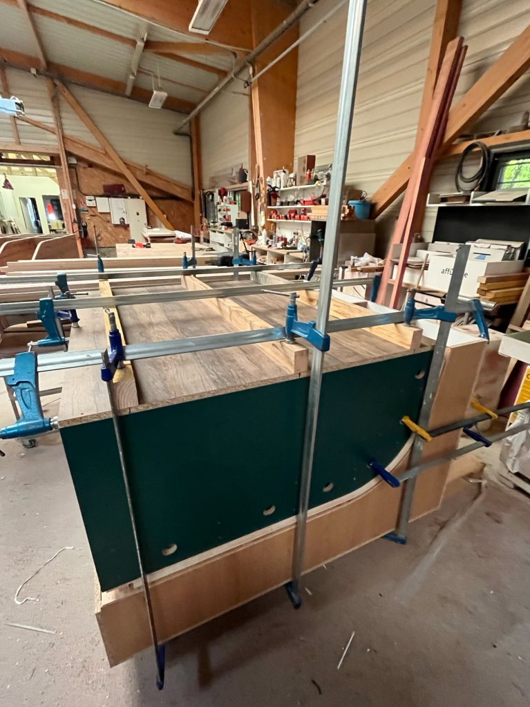 Montage d’une teardrop caravane en atelier : panneaux assemblés et serrés avec des serre-joints sur la coque, étape de collage et ajustement des courbes.